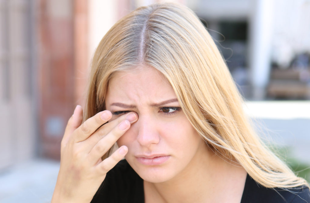 Young woman touching her right eye as she experiences discomfort