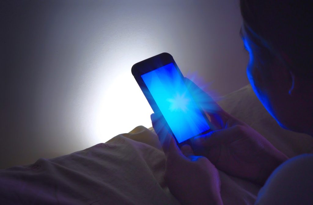 Light coming off smart phone as girl uses it at night