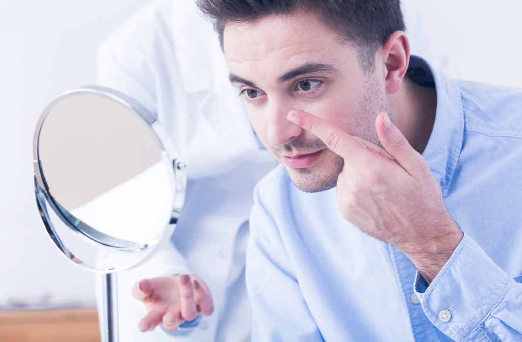 Young man trying on scleral contact lenses at optometrist office