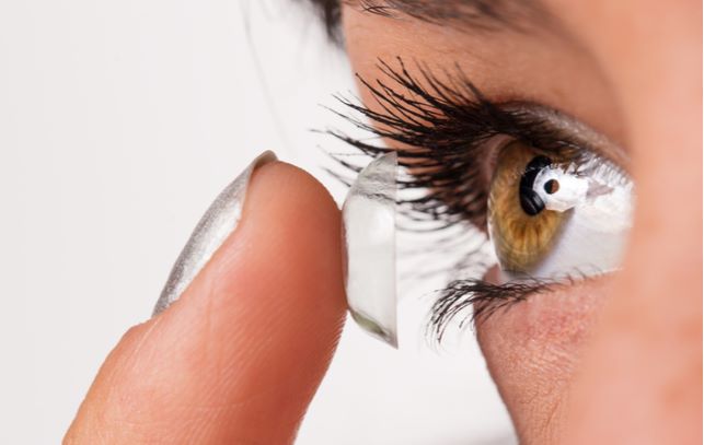 Close up of women with green eyes putting on scleral contact lenses