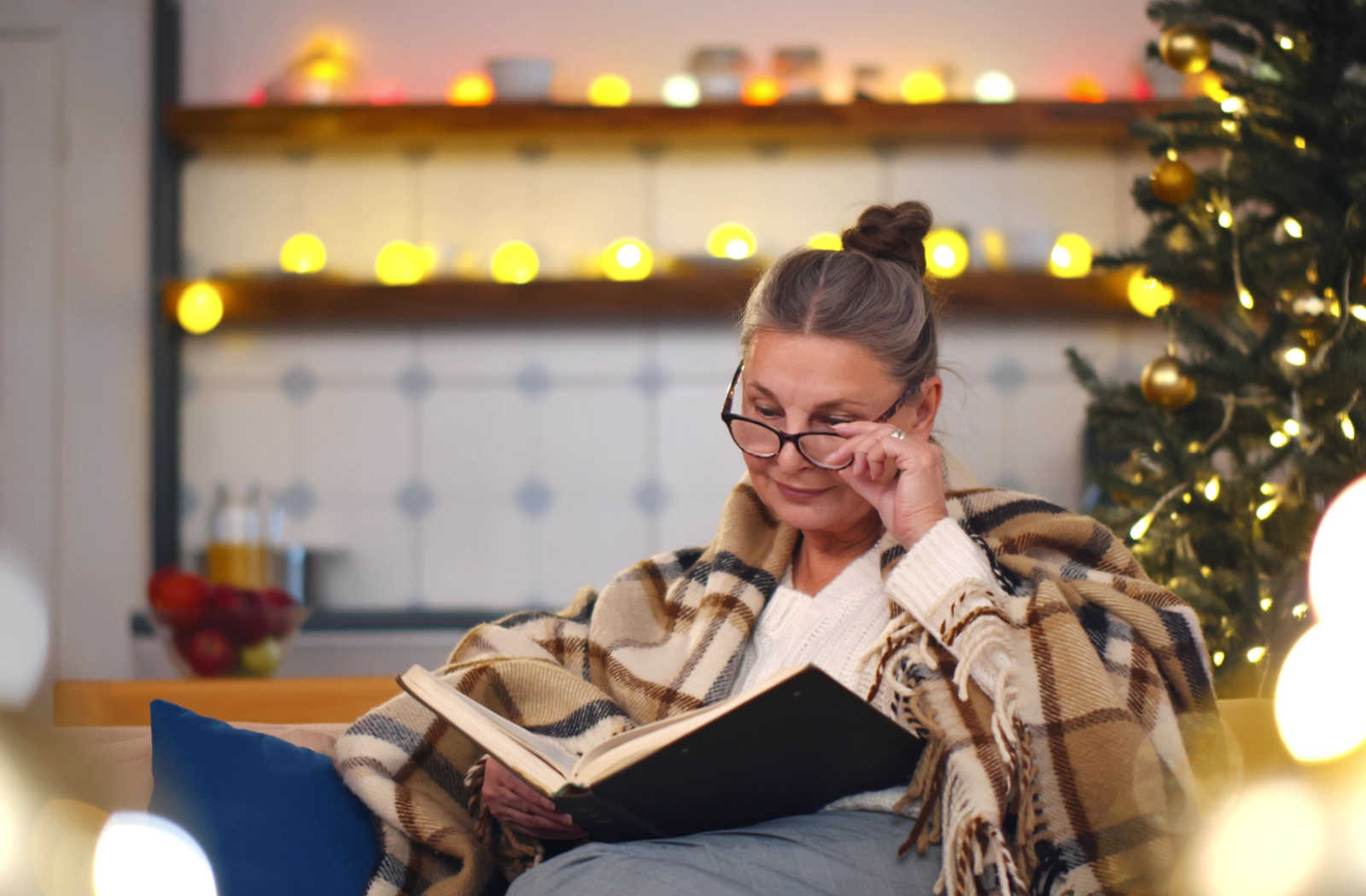 Mature woman reading a book while sitting on a chair.
