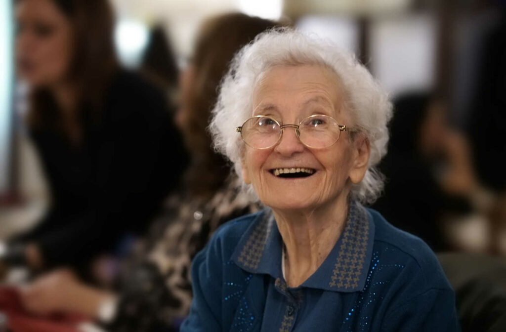 A senior woman smiling with eyeglasses and looking directly at the camera.