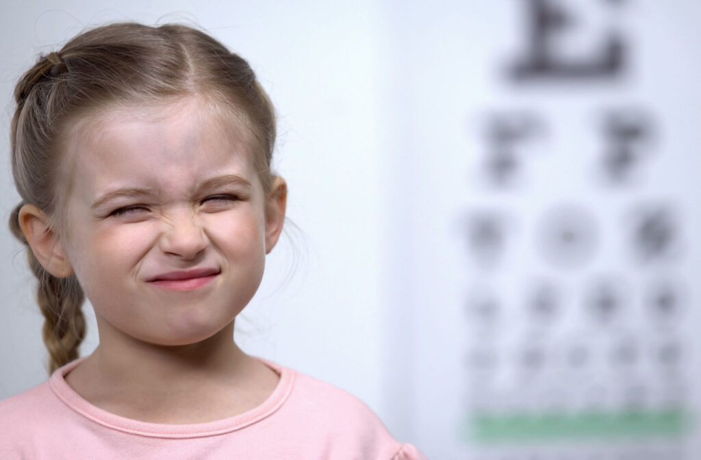A close-up of a child squinting her eyes in the optometrist office.