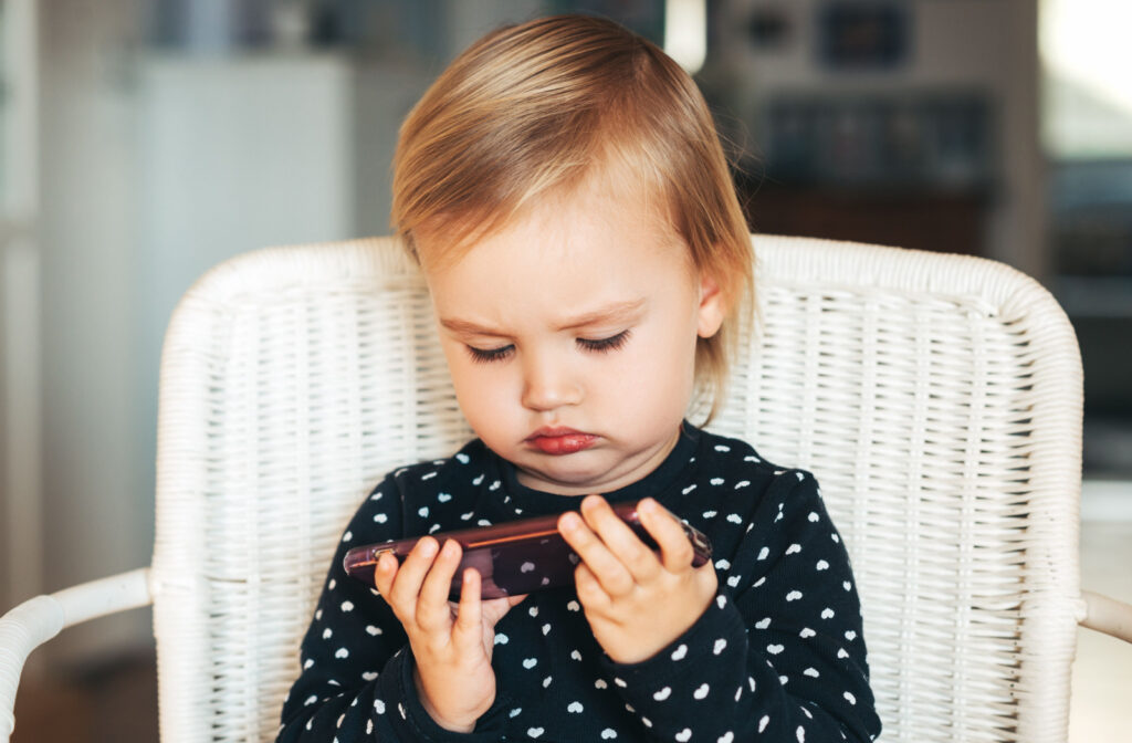 A child holding a smartphone very close to her face.