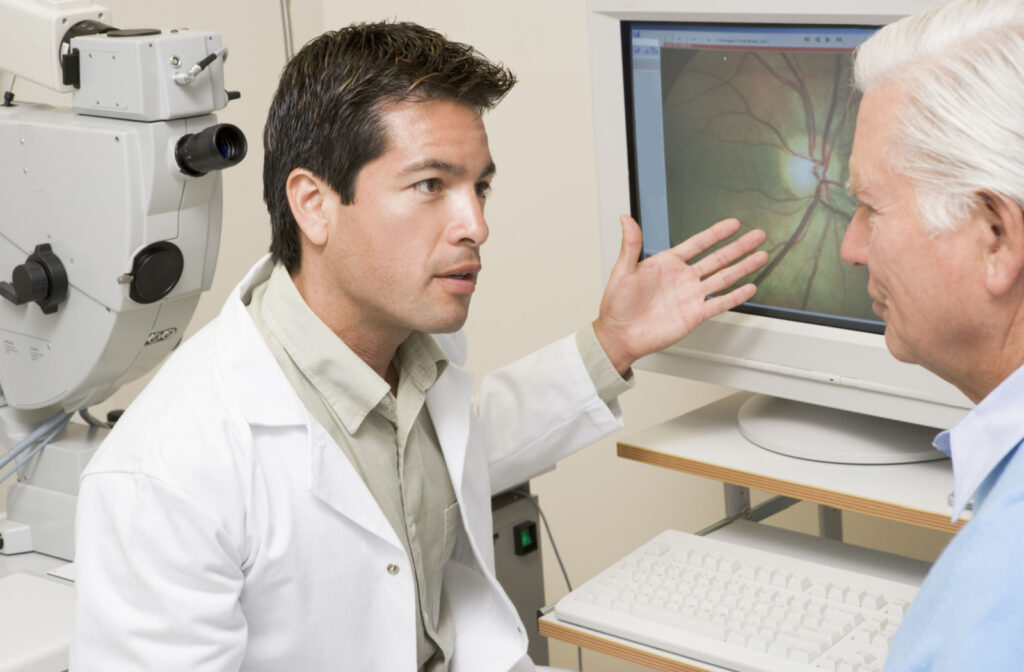Optometrist showing an older male patient a retinal image on a computer screen.