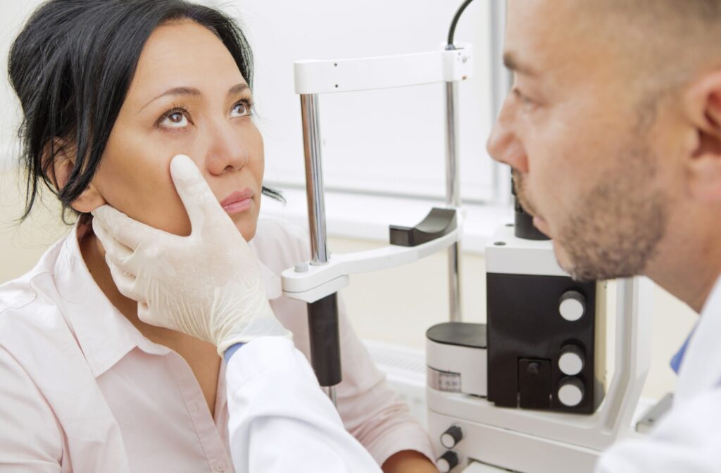 An eye doctor holding down the right lower eyelid of his patient to check its health.