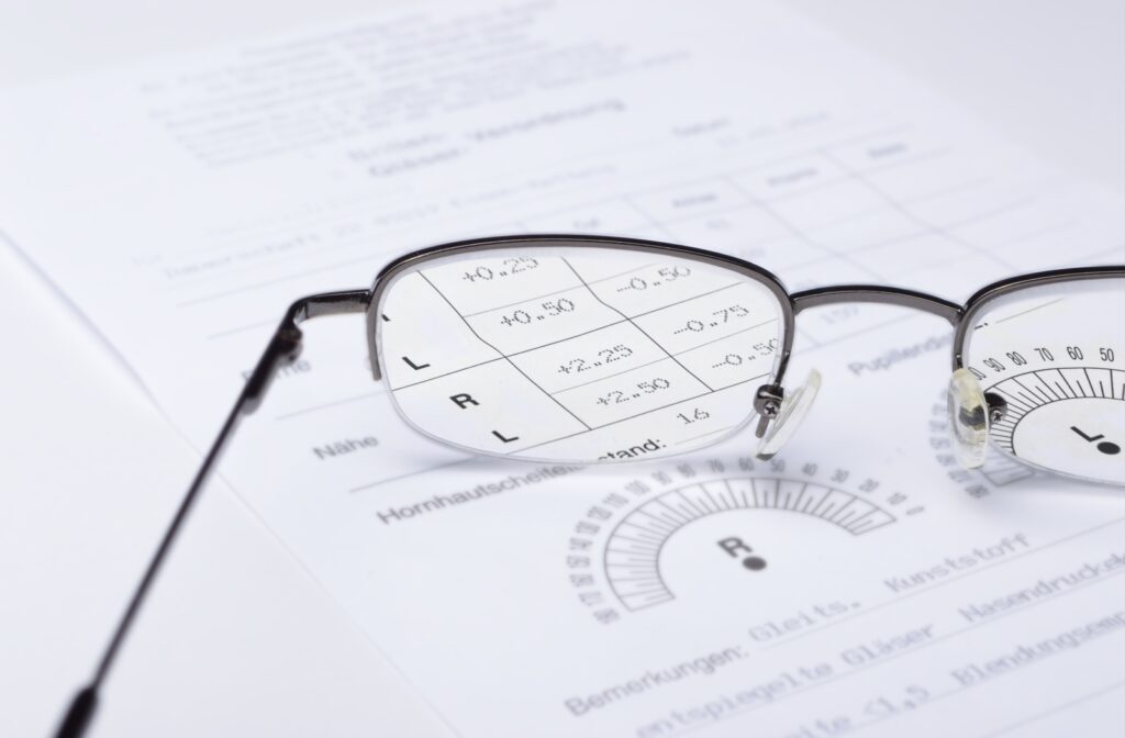 A pair of glasses sitting on top of a prescription for lenses, magnifying the text on the page.