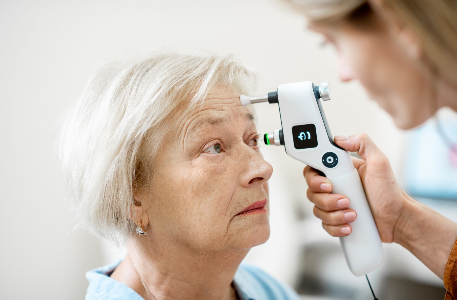 Older woman having eye pressure tested with handheld tonometer.