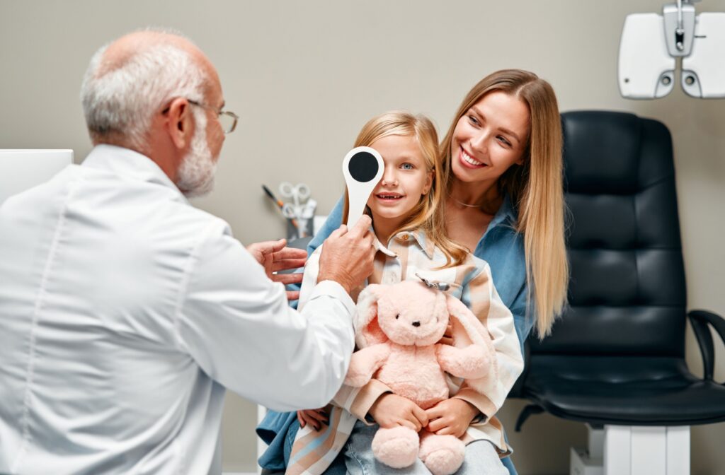 An optometrist evaluates their young patient's vision during their annual eye exam.