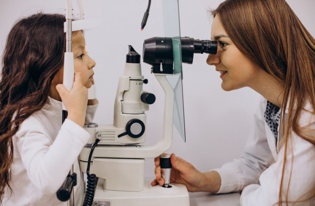 A child undergoing an eye exam with an optometrist using a slit lamp in a clinic.