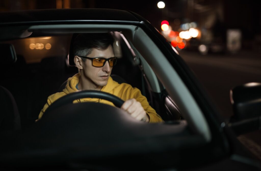An adult driving at night while wearing yellow-tinted driving glasses.