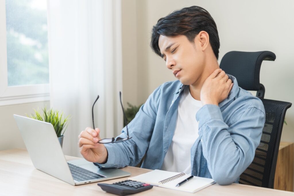 Young adult holding neck from laptop discomfort